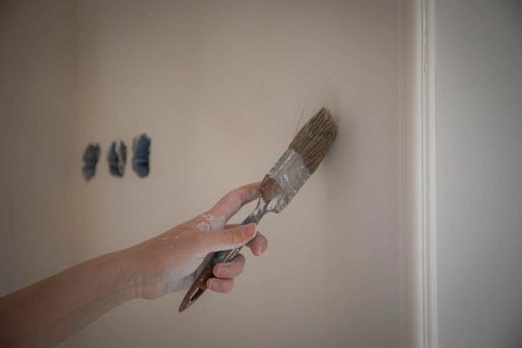 Brush applying paint beside interior trim