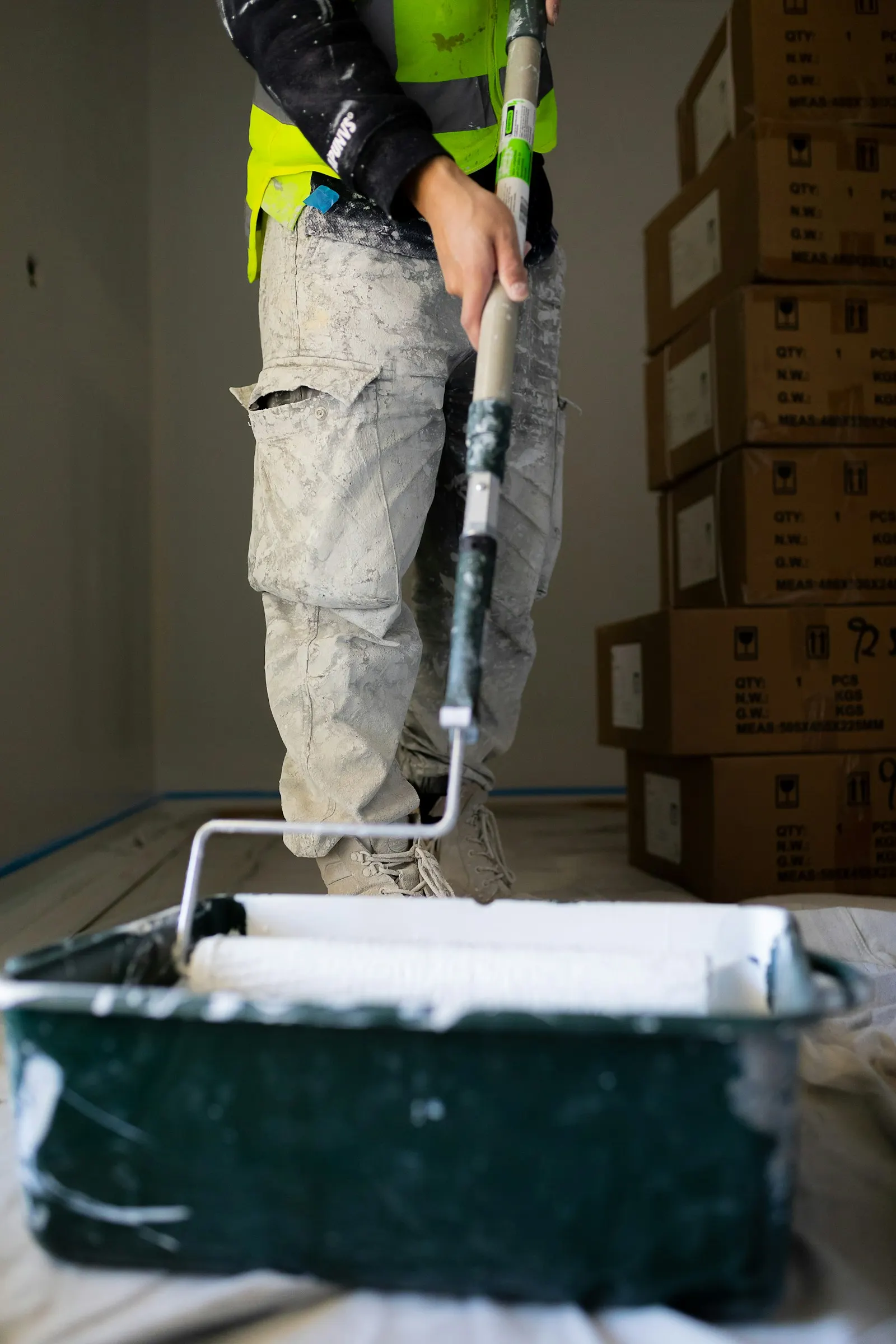 Painter loading a roller before applying paint to an interior wall
