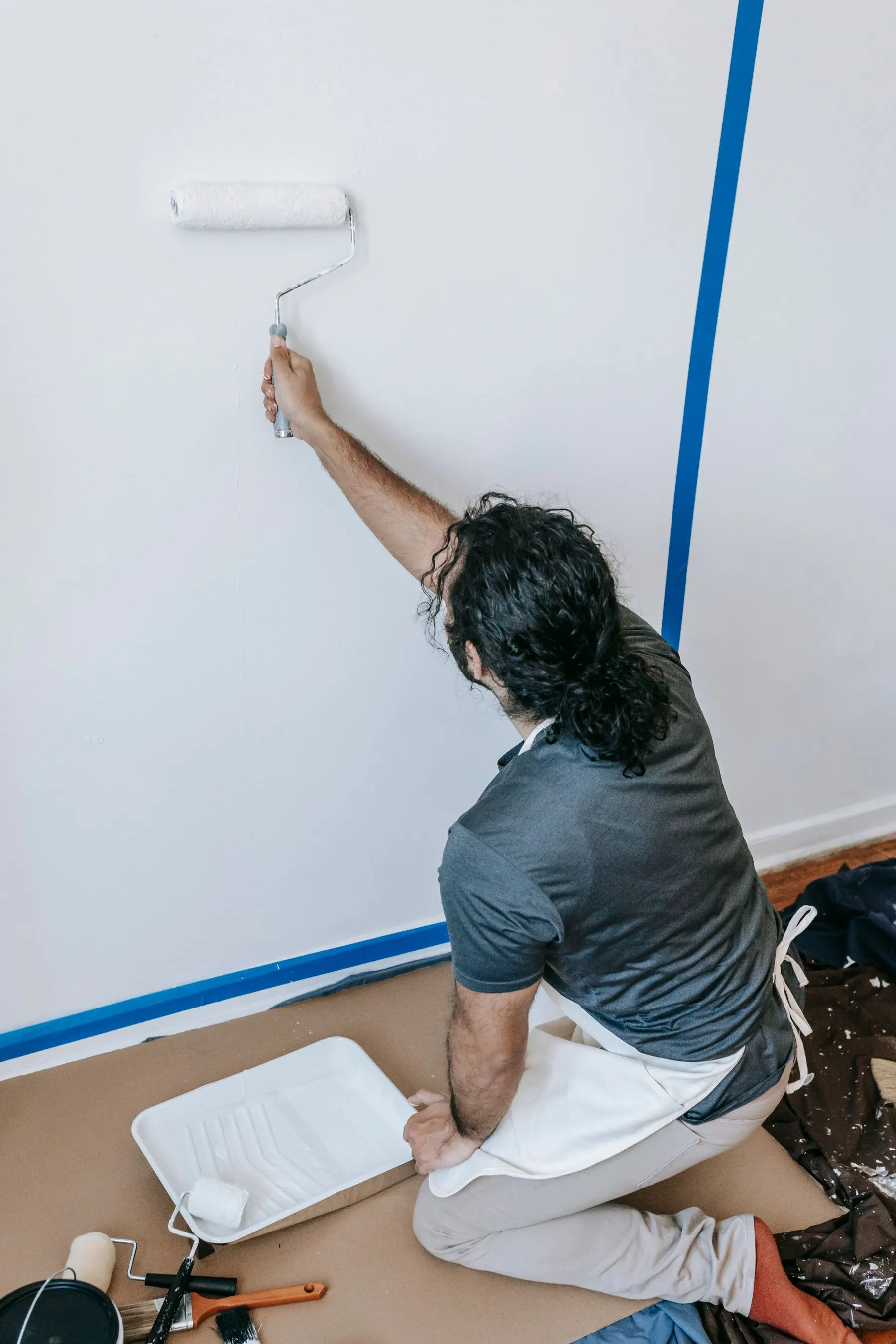 Painter rolling an interior wall with the floor and trim protected